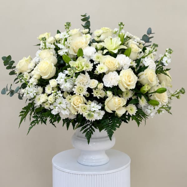White rose and lily arrangement in a white pedestal vase