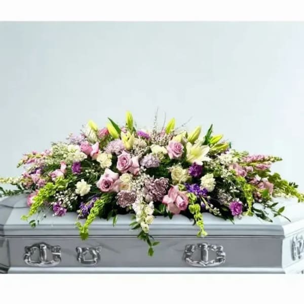 Pastel floral casket spray with roses and lilies on a silver casket