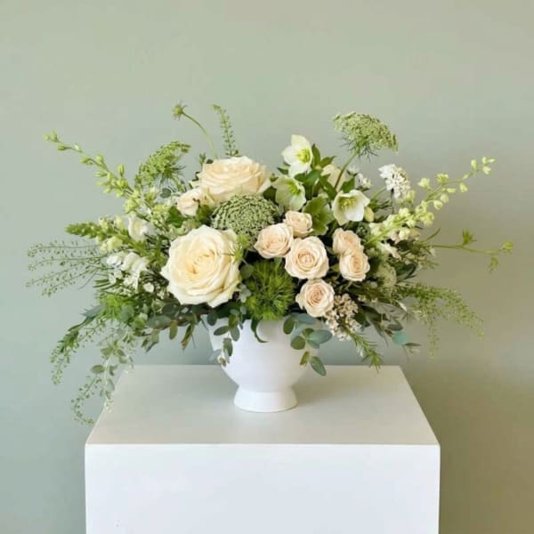 White rose arrangement in a white vase with airy greenery