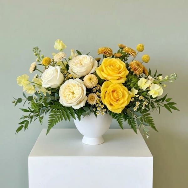 Yellow and white rose arrangement in a white vase