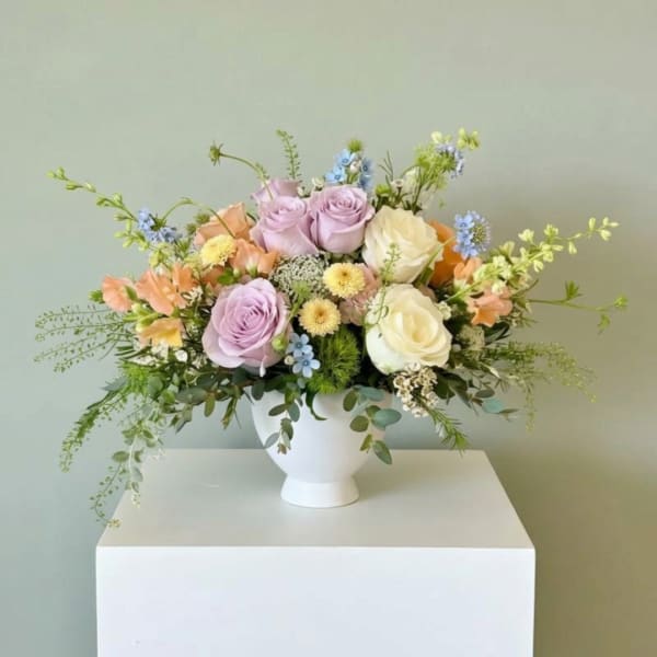 Pastel rose arrangement in a white pedestal vase