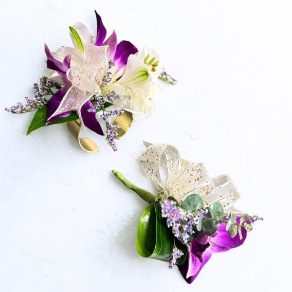 Two purple and white floral boutonnieres with ribbon on a white background