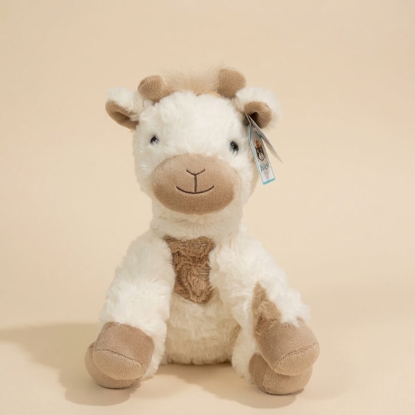 Plush stuffed cow toy sitting against a plain beige background