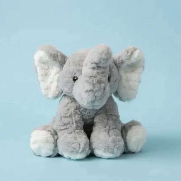 Gray plush elephant toy sitting against a light blue background