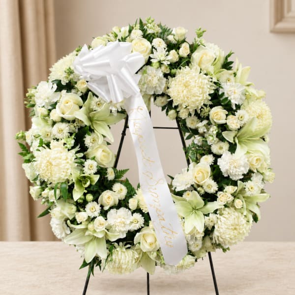 White floral wreath with a satin bow on a stand