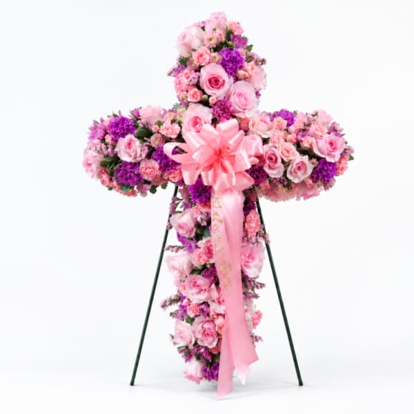 Pink and purple floral cross on a stand with a pink ribbon