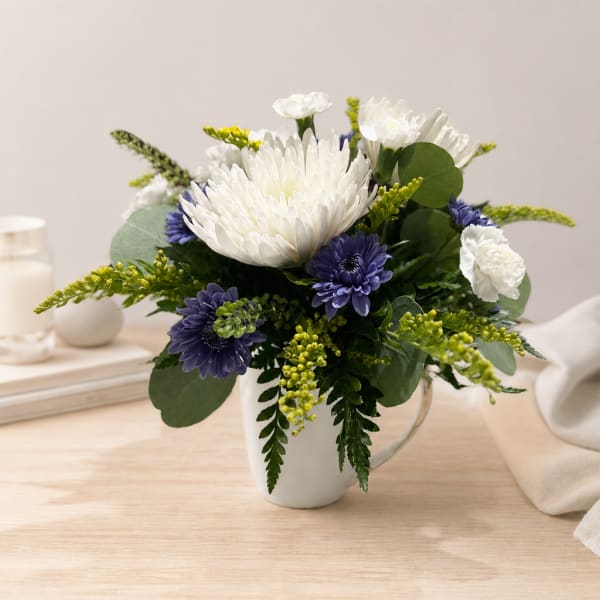 White and purple flowers arranged in a white mug vase