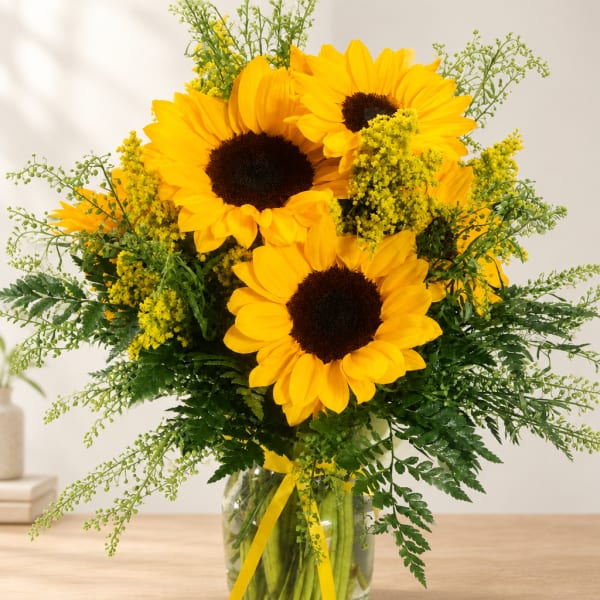 Sunflower bouquet in a clear glass vase with yellow ribbon