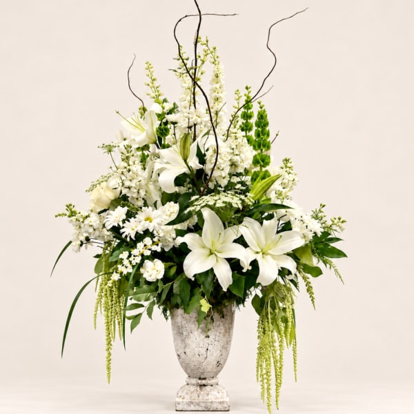 White lilies and mixed white flowers in a tall urn vase