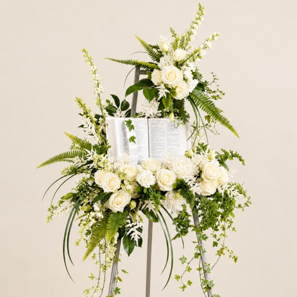 White floral standing arrangement on an easel with an open book centerpiece
