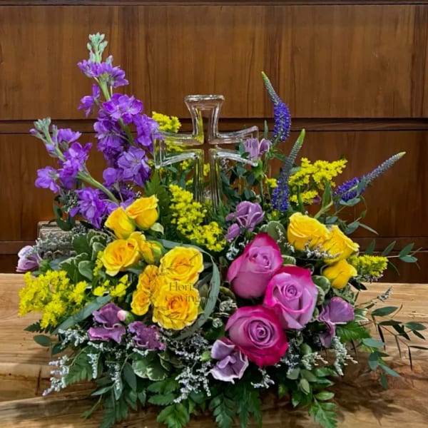 Colorful floral arrangement with roses and a clear glass cross centerpiece