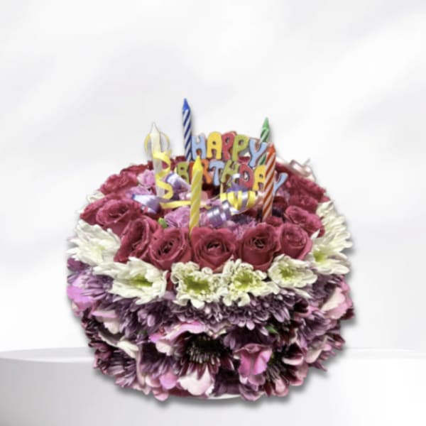 Birthday cake made of flowers with candles and a "Happy Birthday" topper