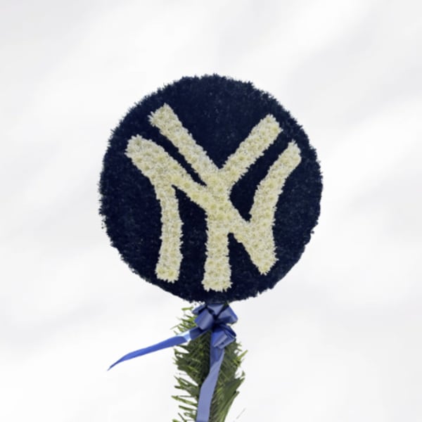 Round floral tribute with a white New York Yankees logo and blue ribbon