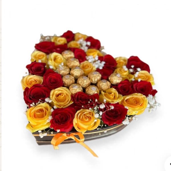 Heart-shaped box of red and yellow roses with chocolates