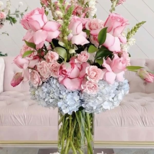 Pink roses and pale blue hydrangeas in a clear glass vase