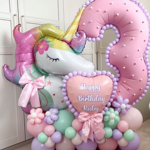 Unicorn birthday balloon display with a pink number 3 and a heart reading Happy Birthday Ruby