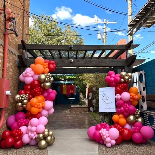 Colorful balloon arch framing an outdoor entrance with a welcome sign