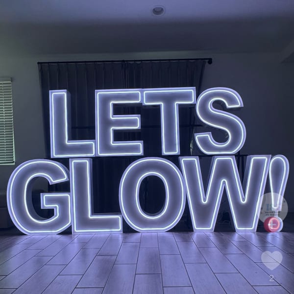Large neon-style sign reading "LETS GLOW" in a room