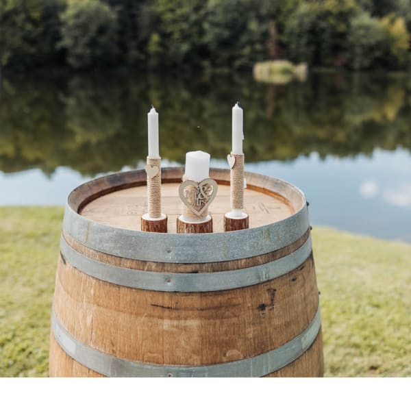 Three white candles on a wooden barrel by the water