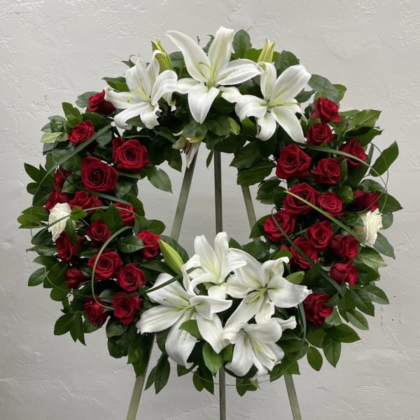 Circular wreath of red roses and white lilies on a stand