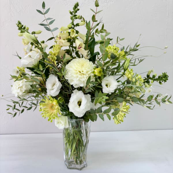 White and pale green floral arrangement in a clear glass vase