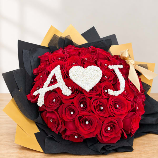 Red rose bouquet with white "A ♥ J" lettering and a gold ribbon