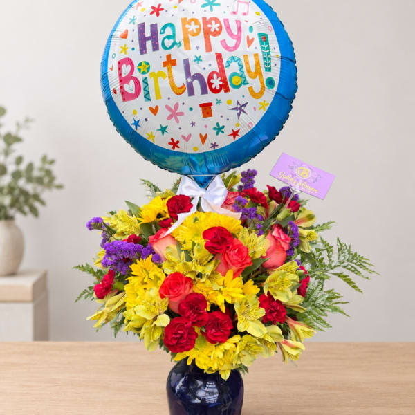 Birthday balloon above a colorful flower arrangement in a vase