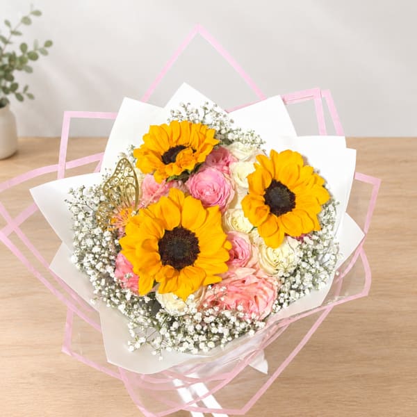 Bouquet of sunflowers and pink roses wrapped in white paper with pink trim