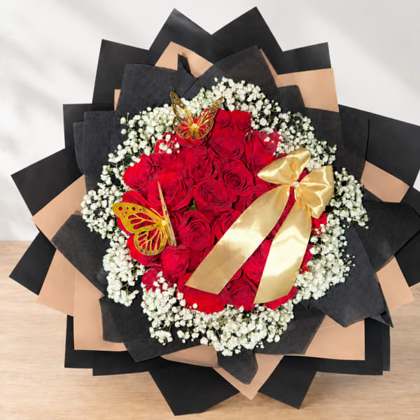 Red rose bouquet with white baby's breath, black wrapping, and a gold ribbon