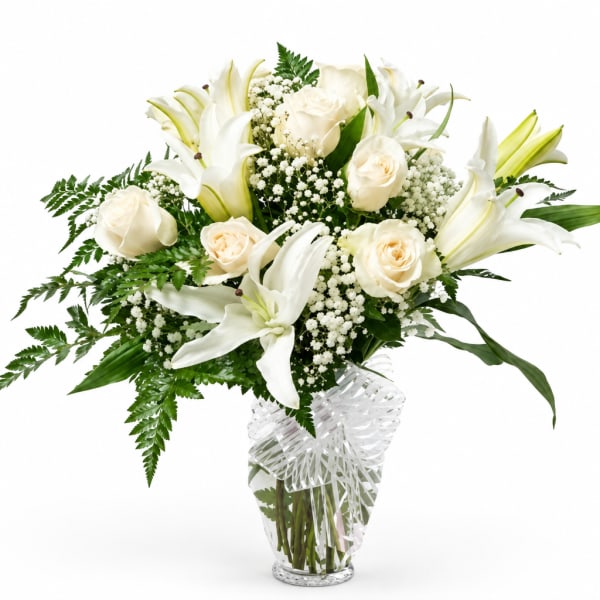 White lilies and roses in a clear glass vase with baby's breath