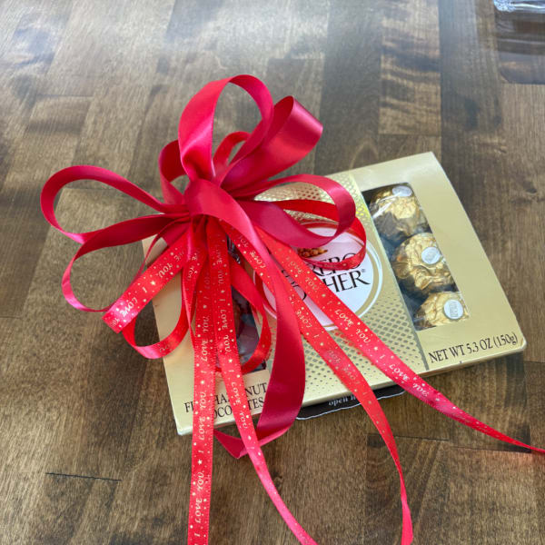 Box of Ferrero Rocher chocolates tied with a large red ribbon