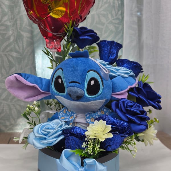 Blue Stitch plush surrounded by blue flowers in a gift box