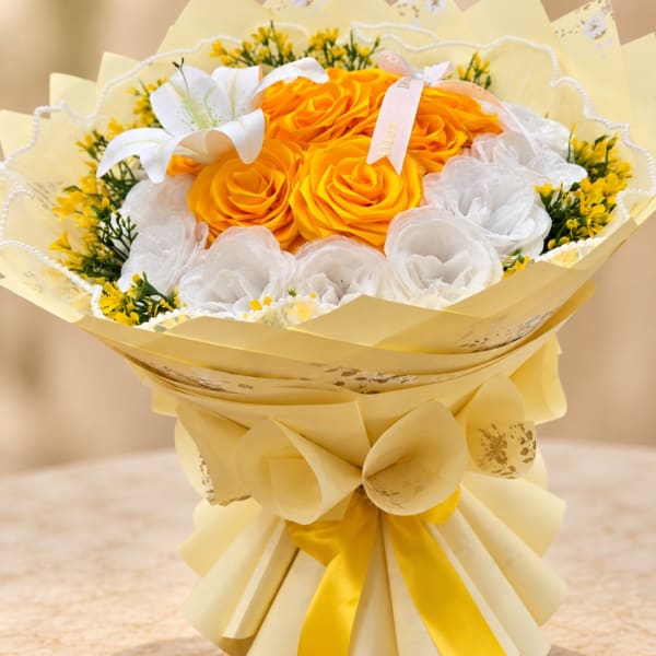 Yellow and white bouquet wrapped in pale paper with a ribbon