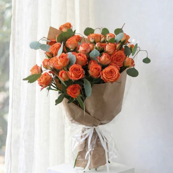 Bouquet of orange roses wrapped in brown paper