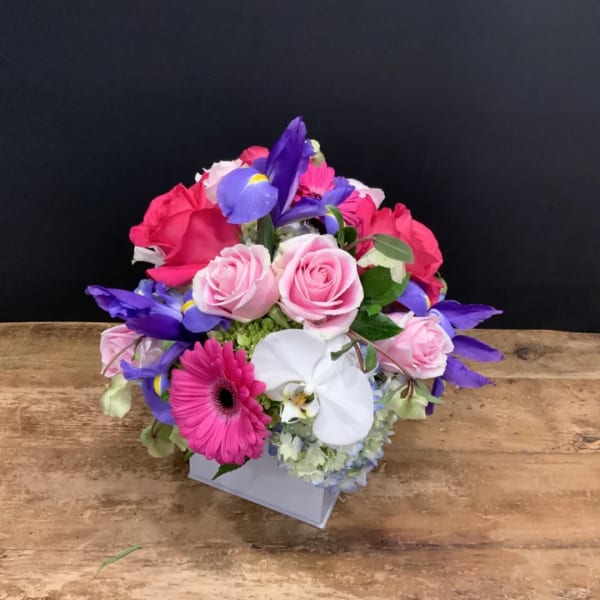 Mixed bouquet with pink roses, purple irises, and a white orchid in a box