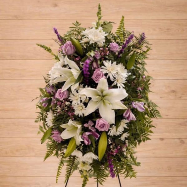 Standing floral wreath with white lilies, lavender roses, and purple accents