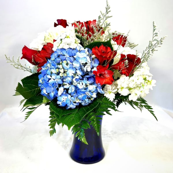 Red, white, and blue flower arrangement in a blue vase