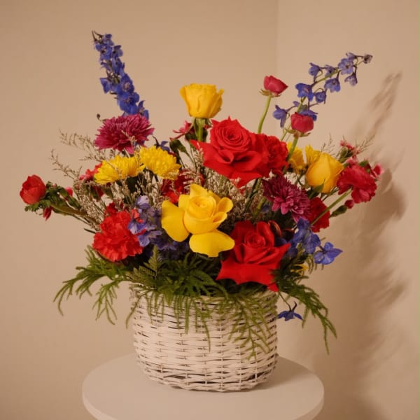 Colorful mixed flower arrangement in a white woven basket