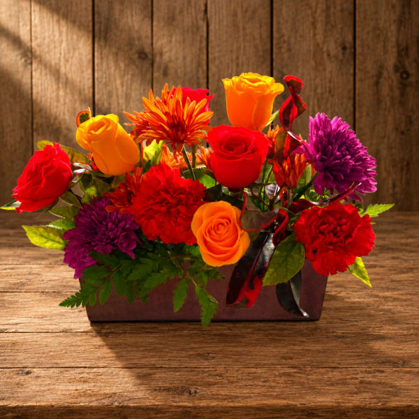 Bright mixed bouquet in a rectangular container with roses and mums