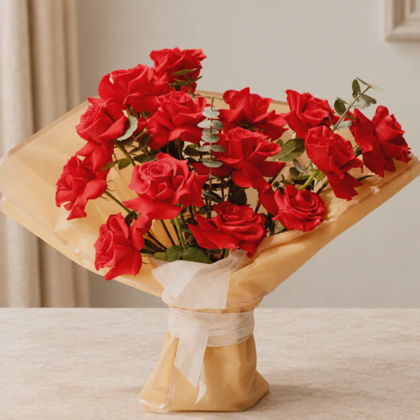 Bouquet of red roses wrapped in tan paper with a white ribbon