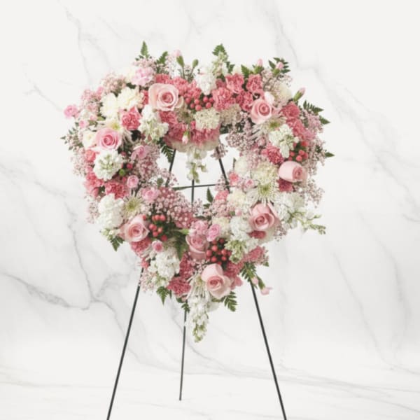 Heart-shaped pink and white floral wreath on a stand