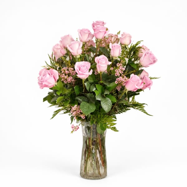 Pink roses arranged in a clear glass vase with greenery
