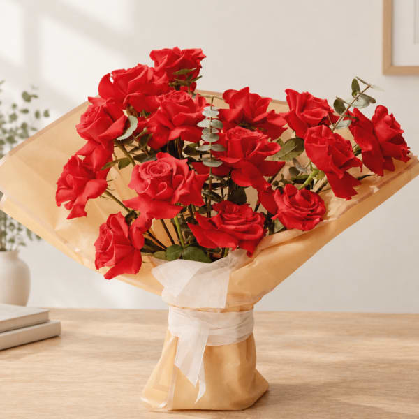 Bouquet of red roses wrapped in tan paper with a white ribbon