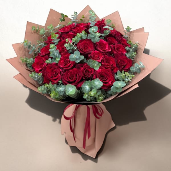 Bouquet of red roses with eucalyptus wrapped in pink paper