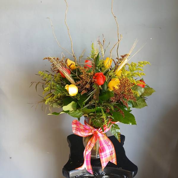 Mixed bouquet of red and yellow roses in a vase with a plaid ribbon