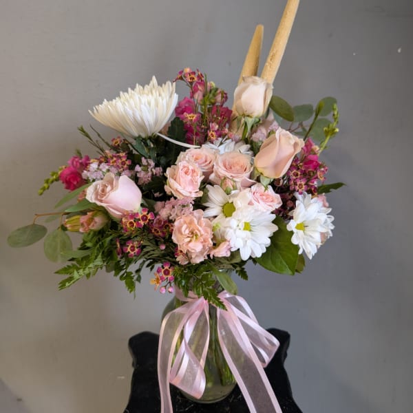 Pink and white mixed bouquet in a glass vase with a pink ribbon