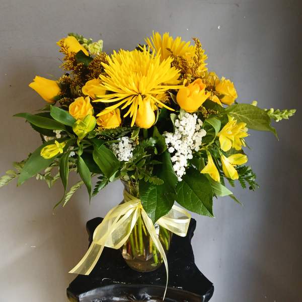 Yellow bouquet in a glass vase with a ribbon bow