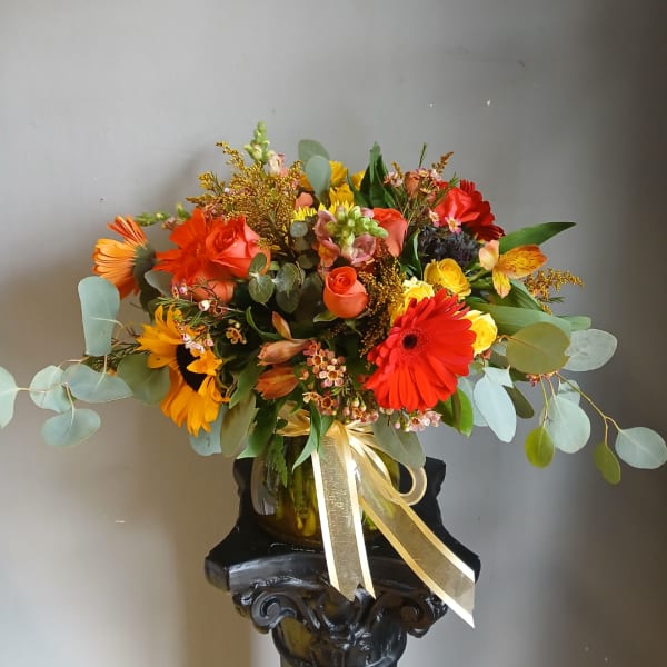 Colorful mixed bouquet in a glass vase with a gold ribbon