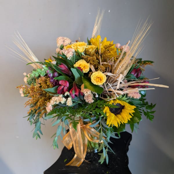 Mixed bouquet with yellow roses and a sunflower in a glass vase