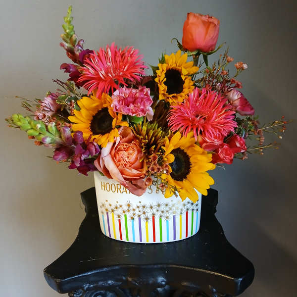 Mixed bouquet with sunflowers, roses, and bright pink blooms in a white box